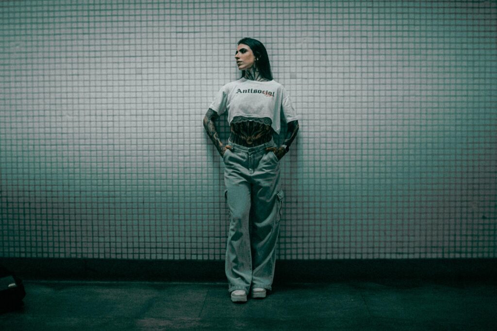 Fashionable woman posing against tiled wall in subway. Edgy style.